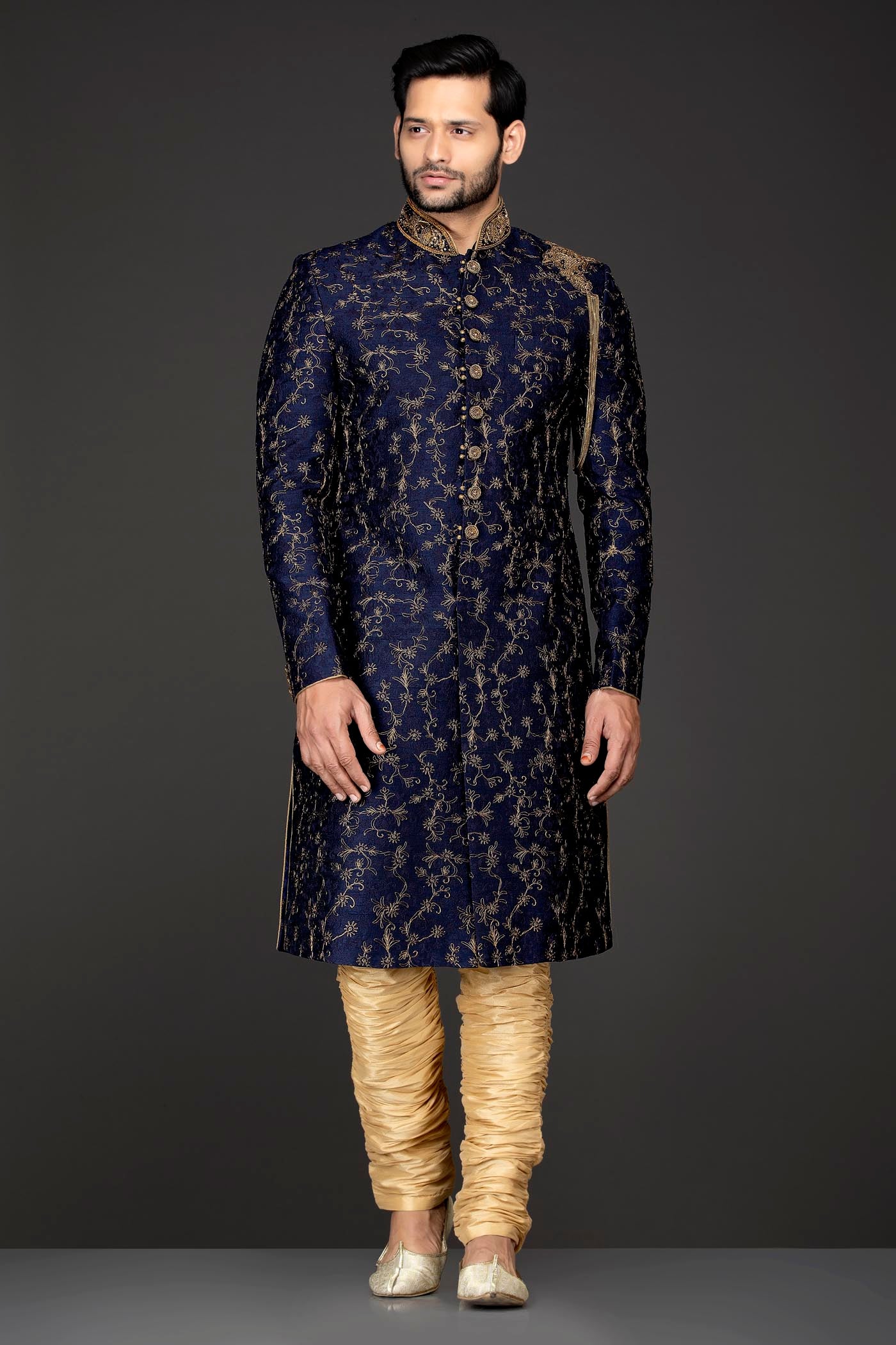 Navy Blue Silk Sherwani With Embroidery On The Collar And Shoulder Brooch With Hanging Tassels Paired With Gold Trousers