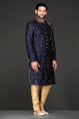 Navy Blue Silk Sherwani With Embroidery On The Collar And Shoulder Brooch With Hanging Tassels Paired With Gold Trousers