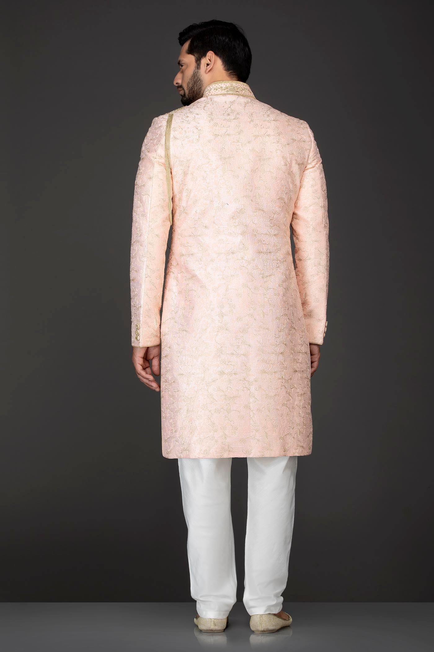 Peach Silk Sherwani With Embroidery On The Collar And Shoulder Brooch With Hanging Tassels Paired With White Trousers